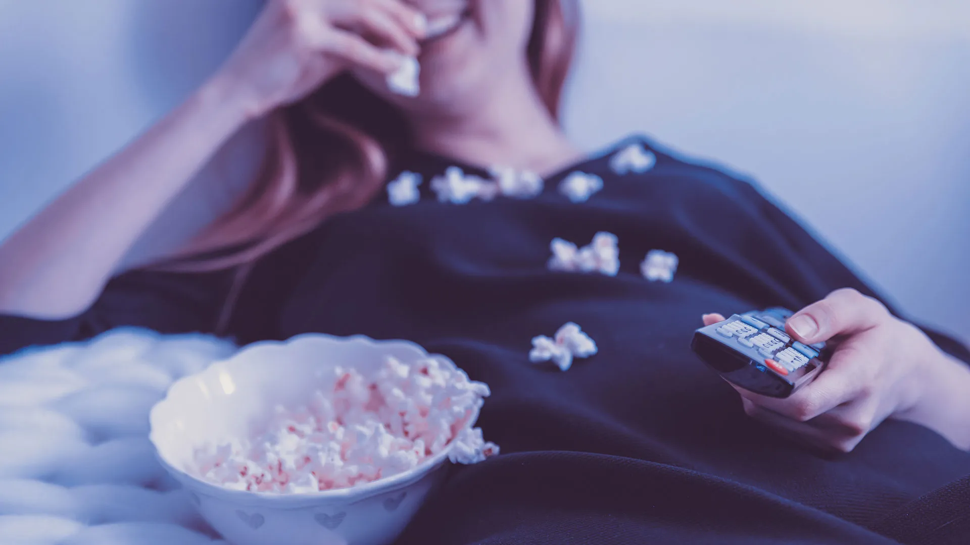 Chica comiendo palomitas viendo la TV