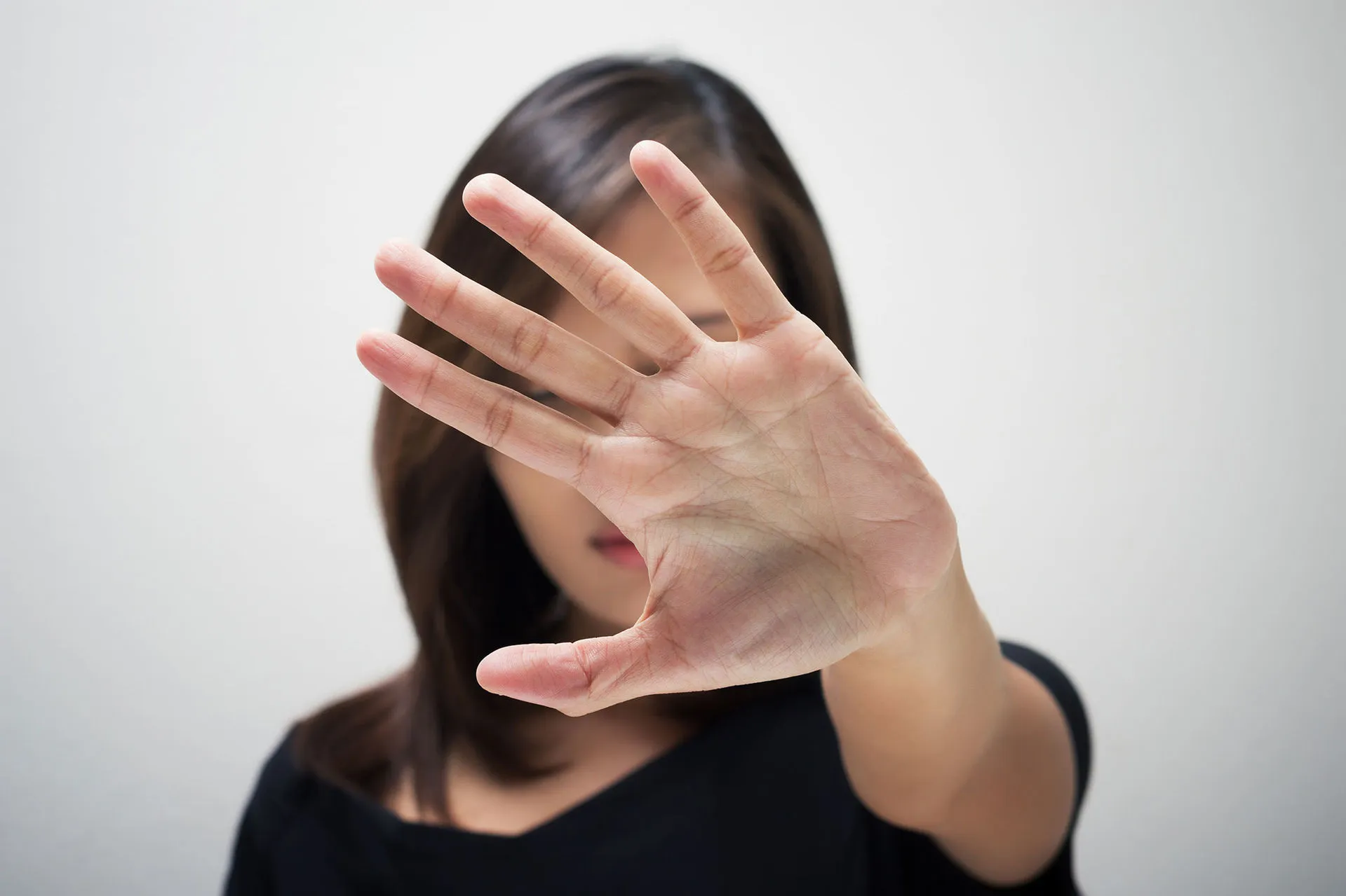Mujer con palma de la mano abierta, en señal de poner un alto a la violencia de género