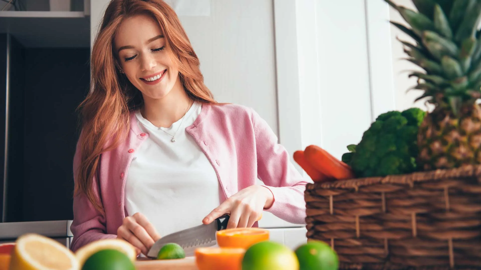 Mujer joven en una cocina cortado un limón con frutas y verduras