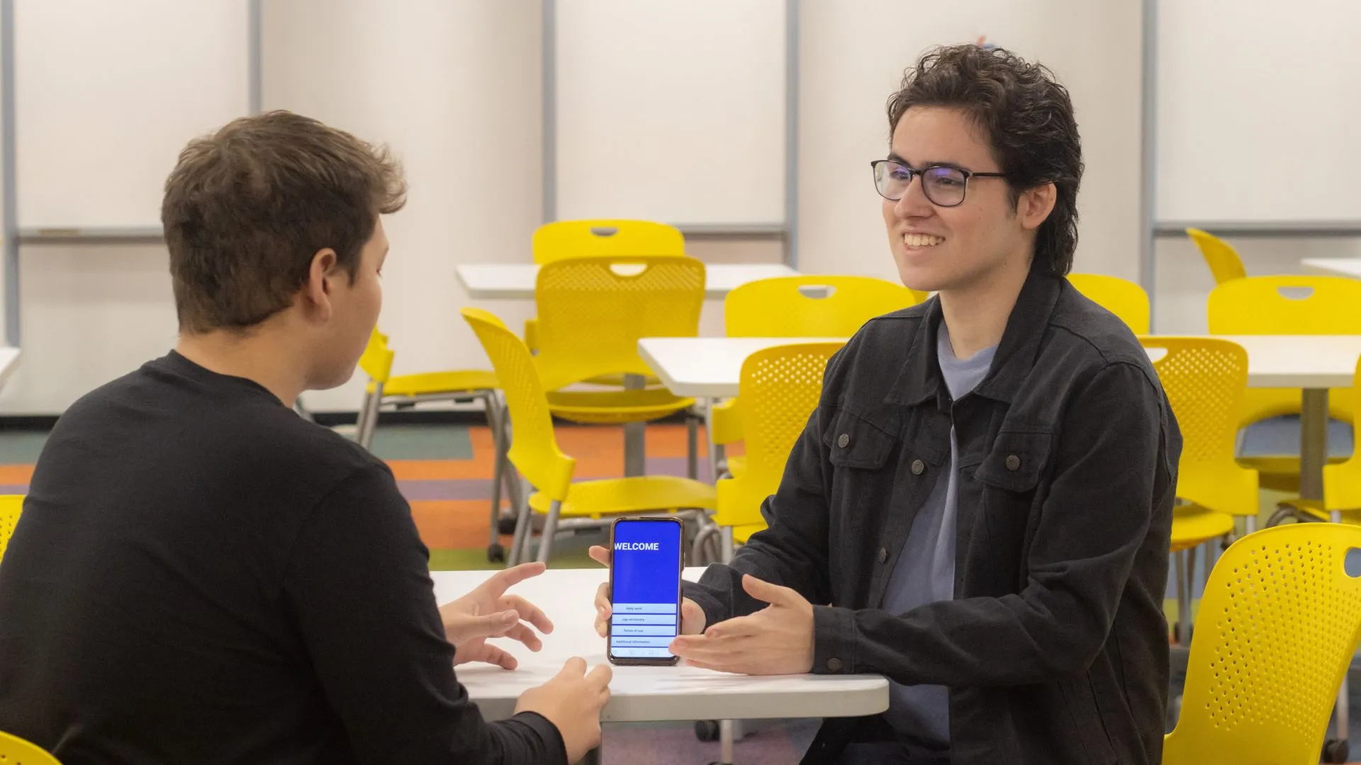 alumno muestra su app de lenguaje de señas en su teléfono