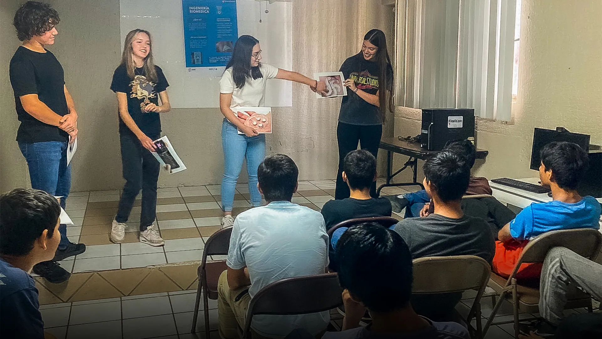 Estudiantes enseñando ciencia frente a un grupo. 