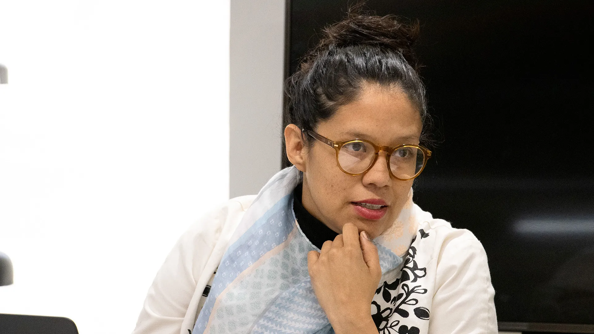 Profesora con lentes, ropa blanca y el cabello sujetado