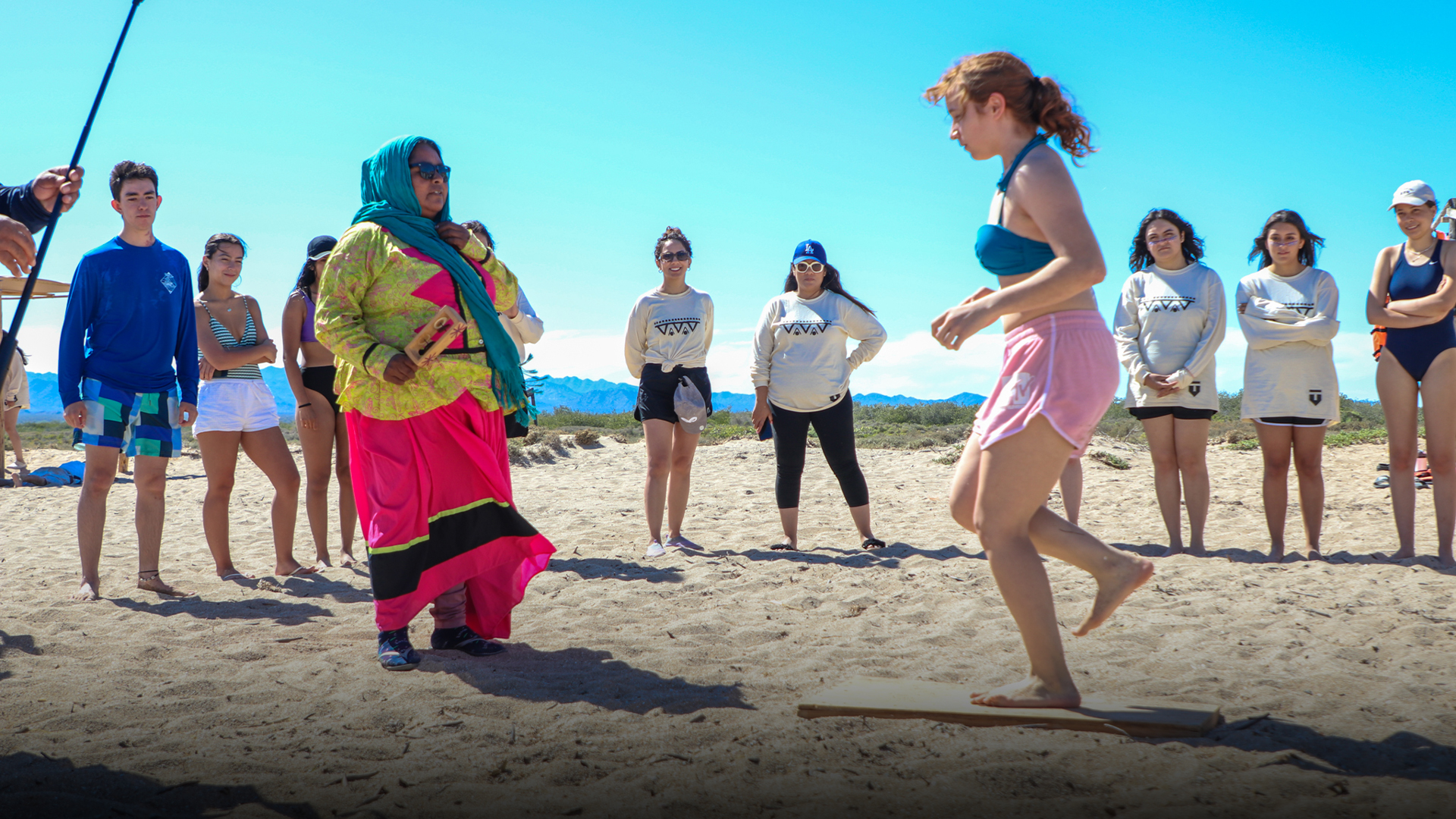 Adolescente hace baile tradicional guiada por un miembro de la comunidad Comca'ac en la playa.
