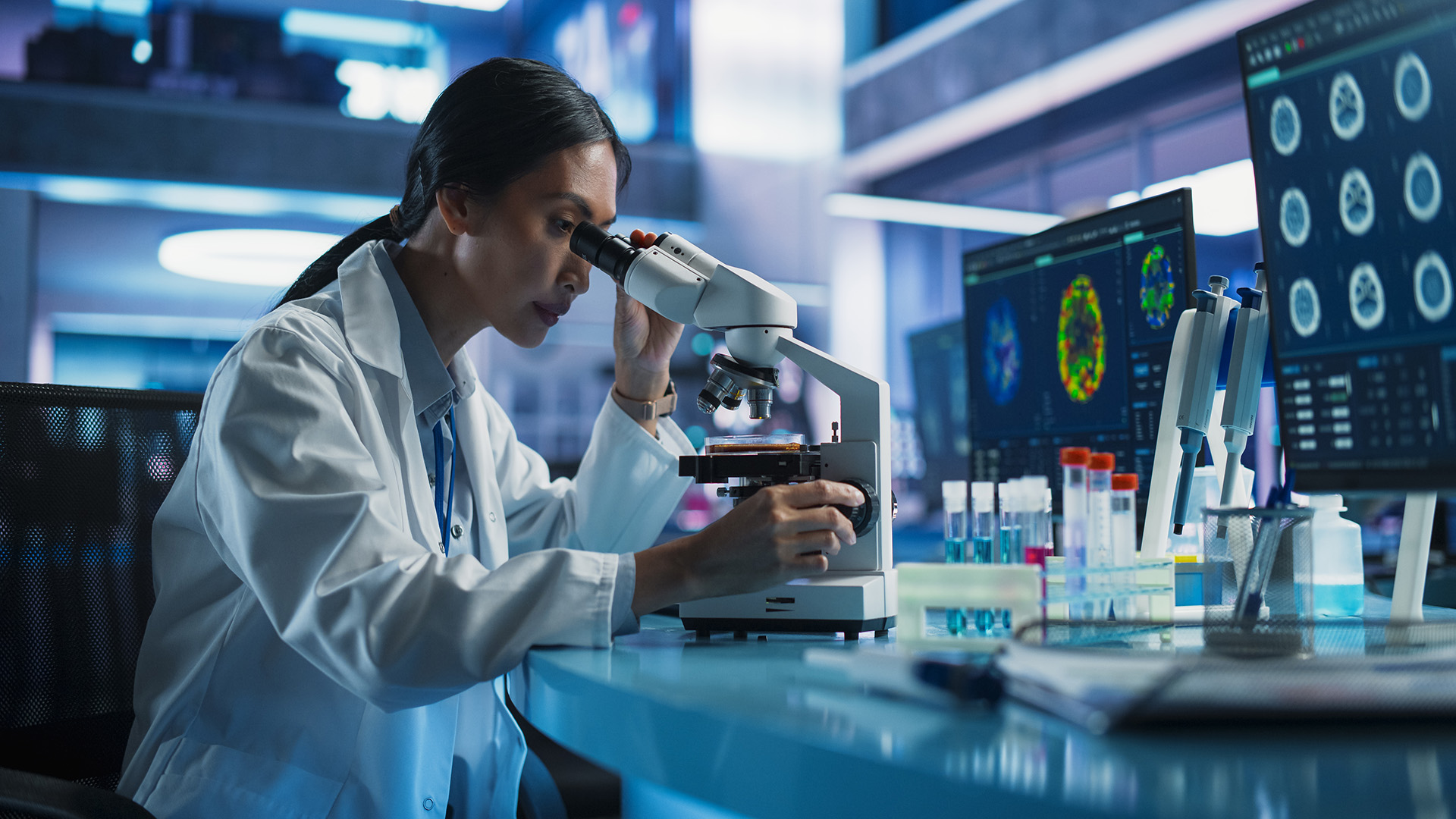 mujer en laboratorio viendo por microscopio