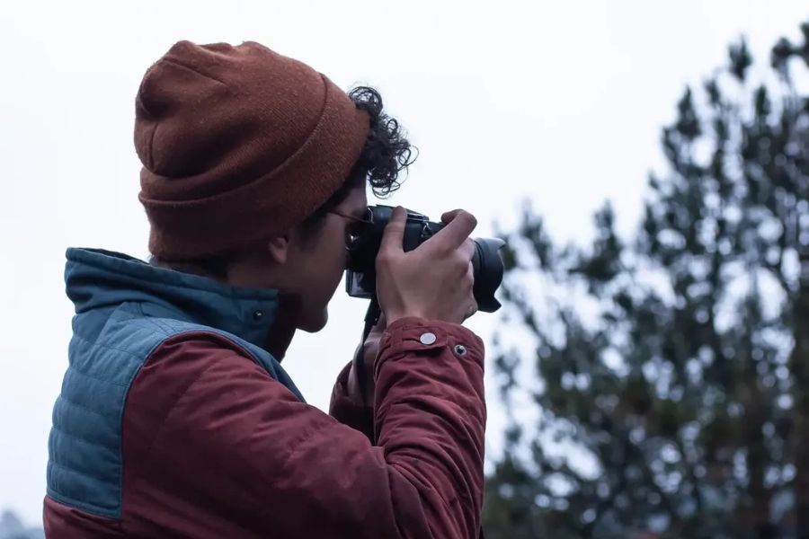 Pepe Santill&aacute;n sostiene una c&aacute;mara mientras toma una fotograf&iacute;a en un entorno al aire libre.