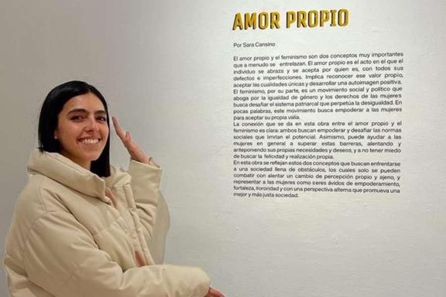 Sara Cansino posando al lado de la explicación del concepto de su exposición
