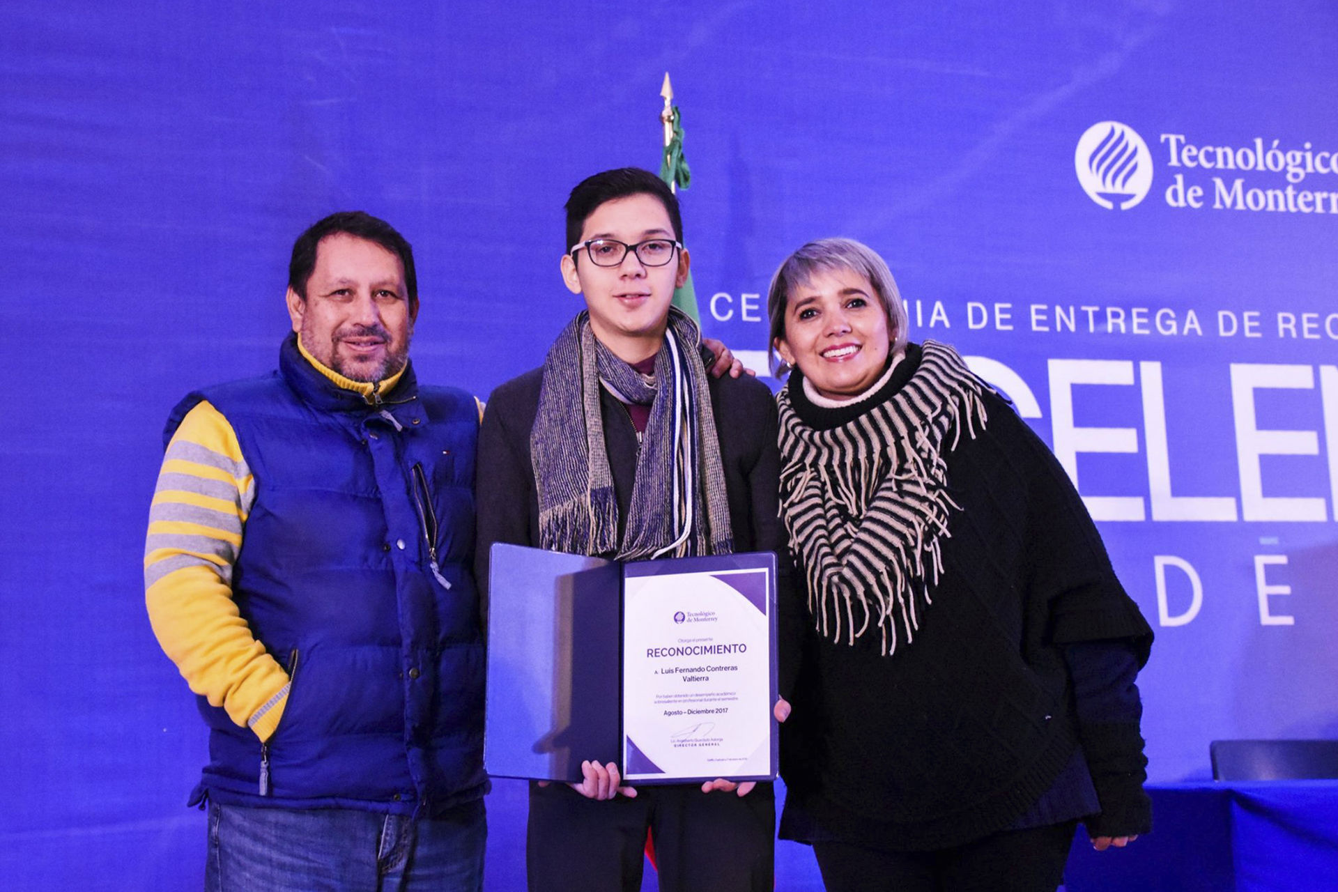 Alumno junto a sus padres sosteniendo un diploma