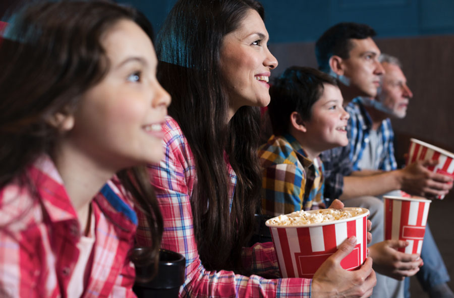 Familia sentada viendo pelicula en casa