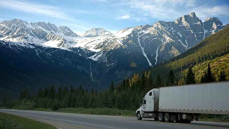 Trailer blanco en carretera con las montañas de fondo