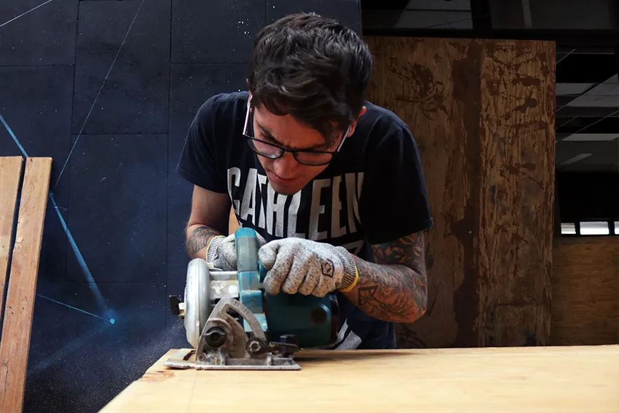 Un joven cortando un pedazo de madera en el nodo.jpg