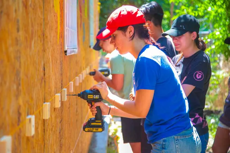 Alumna del Tec sostiene un taladro y trabaja en construcción de aula.