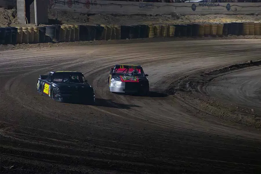 Dos carros corriendo sobre una pista de arcilla.