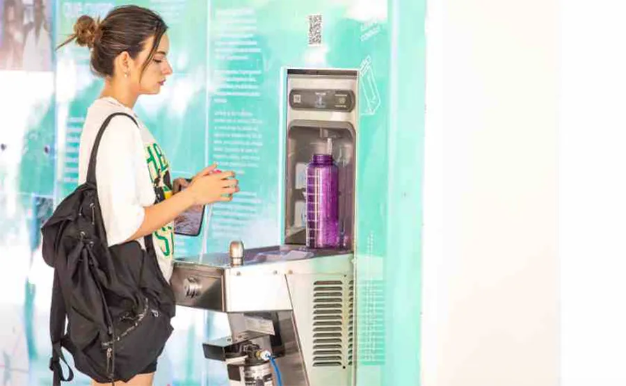 chica joven llenado su termo en el bebedero