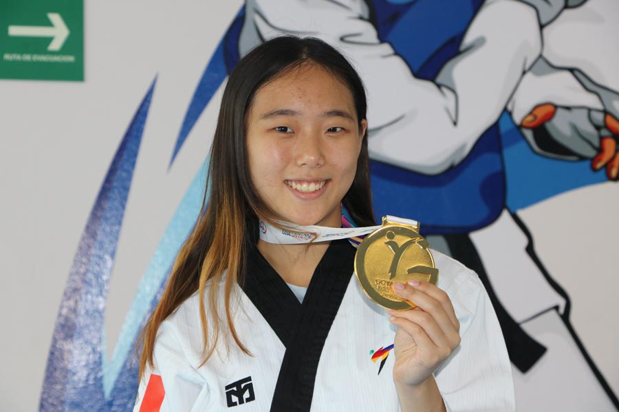 Cecilia Lee sosteniendo su medalla de oro en el Wellness Center.