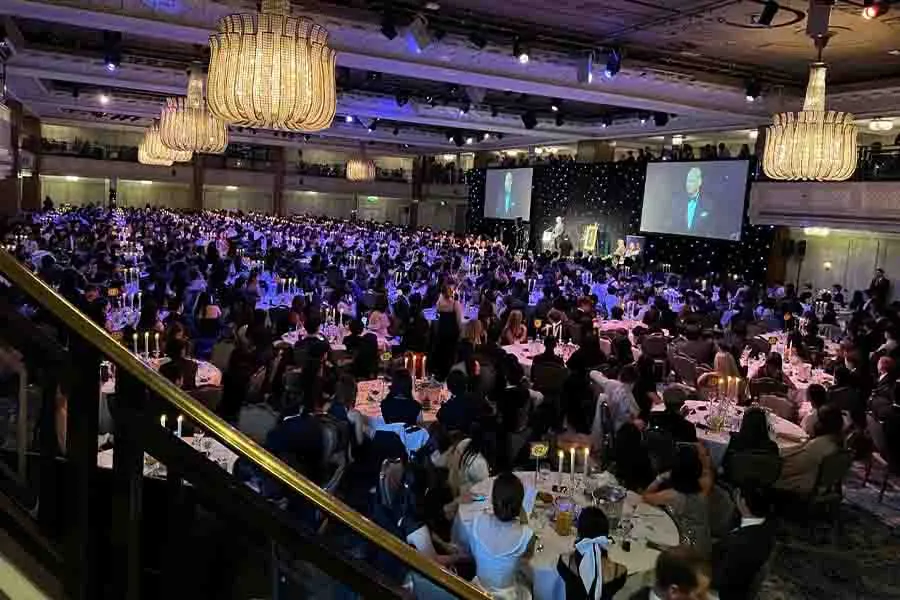 Vista en picada de un salón de eventos con mesas llenas de asistentes. 