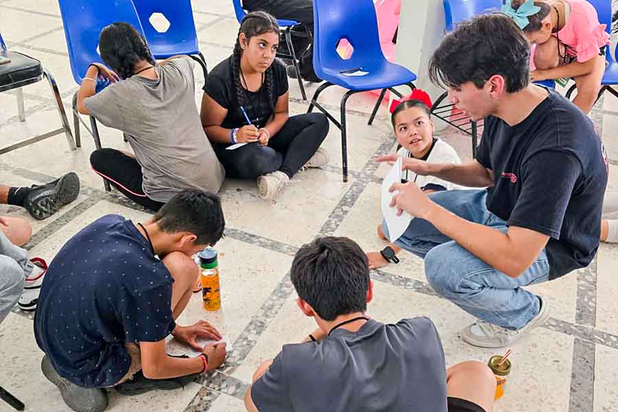 Un joven sentado junto a un grupo de niños.
