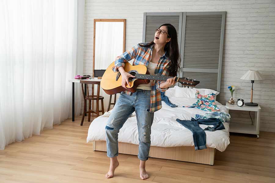 Chica en su cuarto tocando alegremente la guitarra