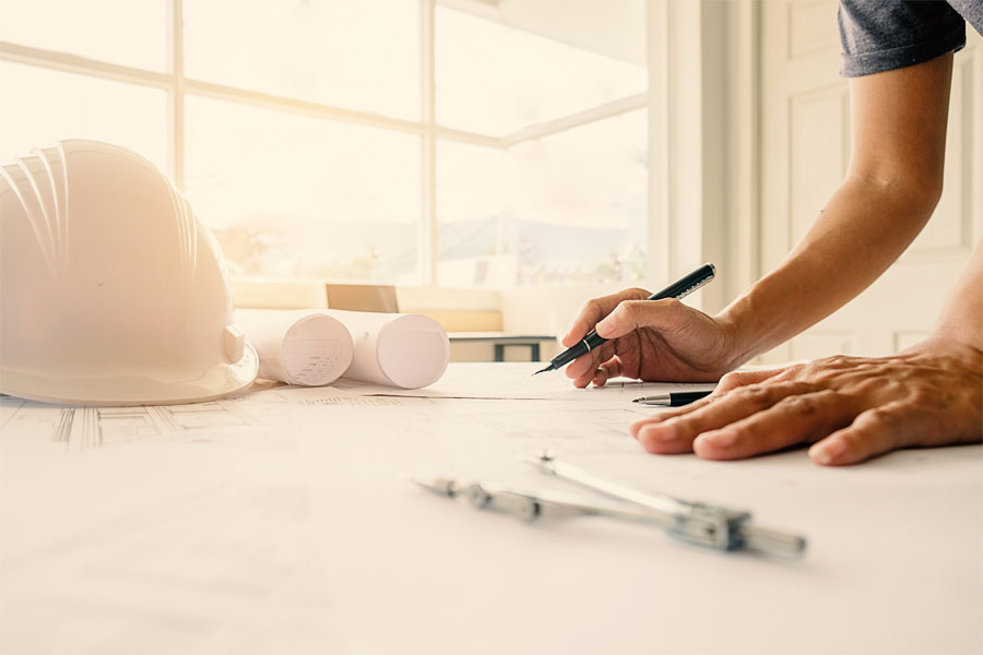 Manos de hombre dibujando sobre plano arquitectónico