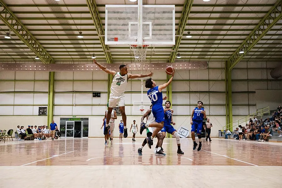 Jugador del equipo campeón de la Liga ADUL enero - junio 2025 de Borregos Laguna intenta encestar ante la defensa de un jugador de Halcones UAL