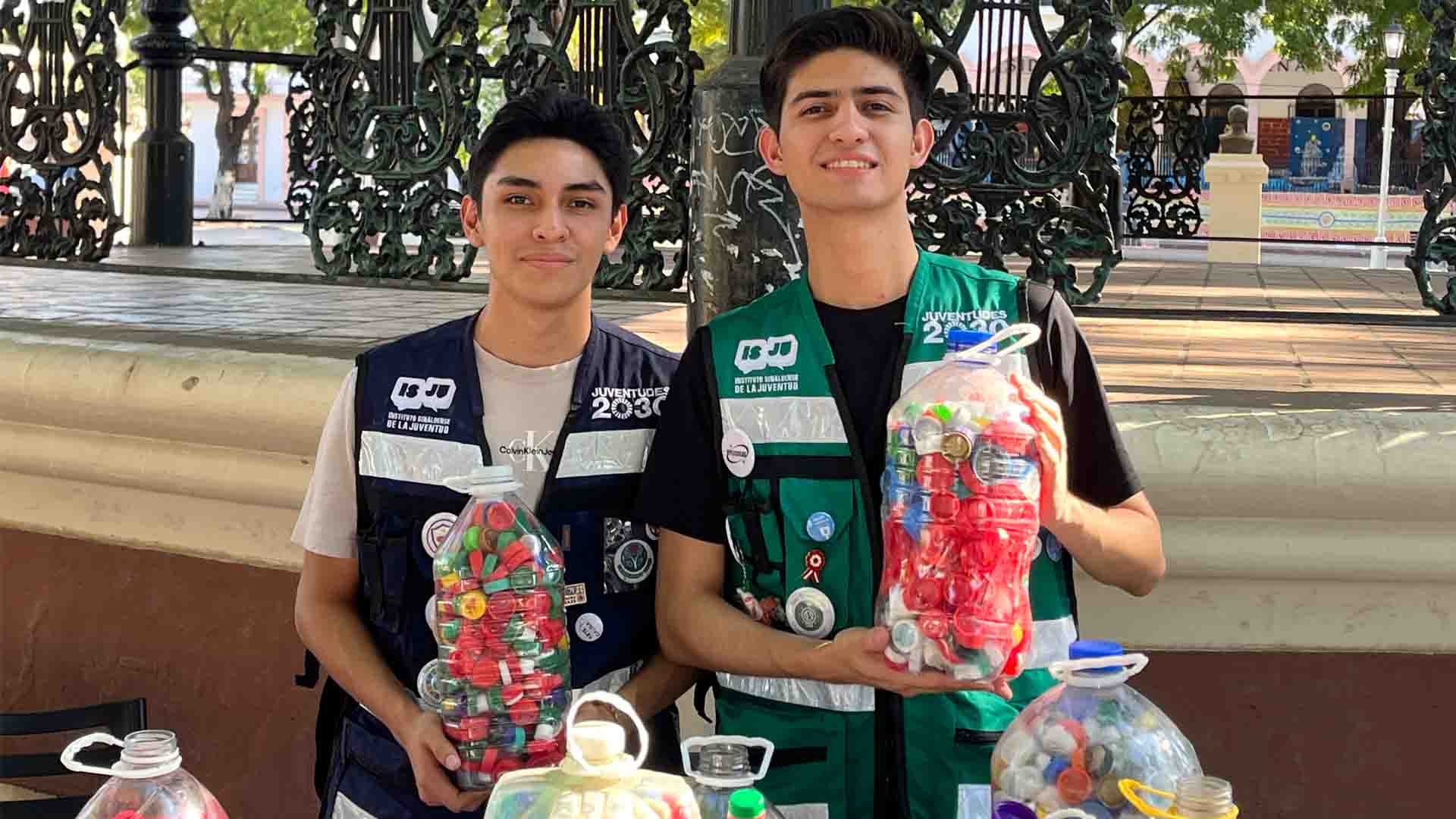 Erick Escamilla e Ismael Cruz sostienen botellas con tapas de pl&aacute;stico durante el evento Recicla Sinaloa 2030.