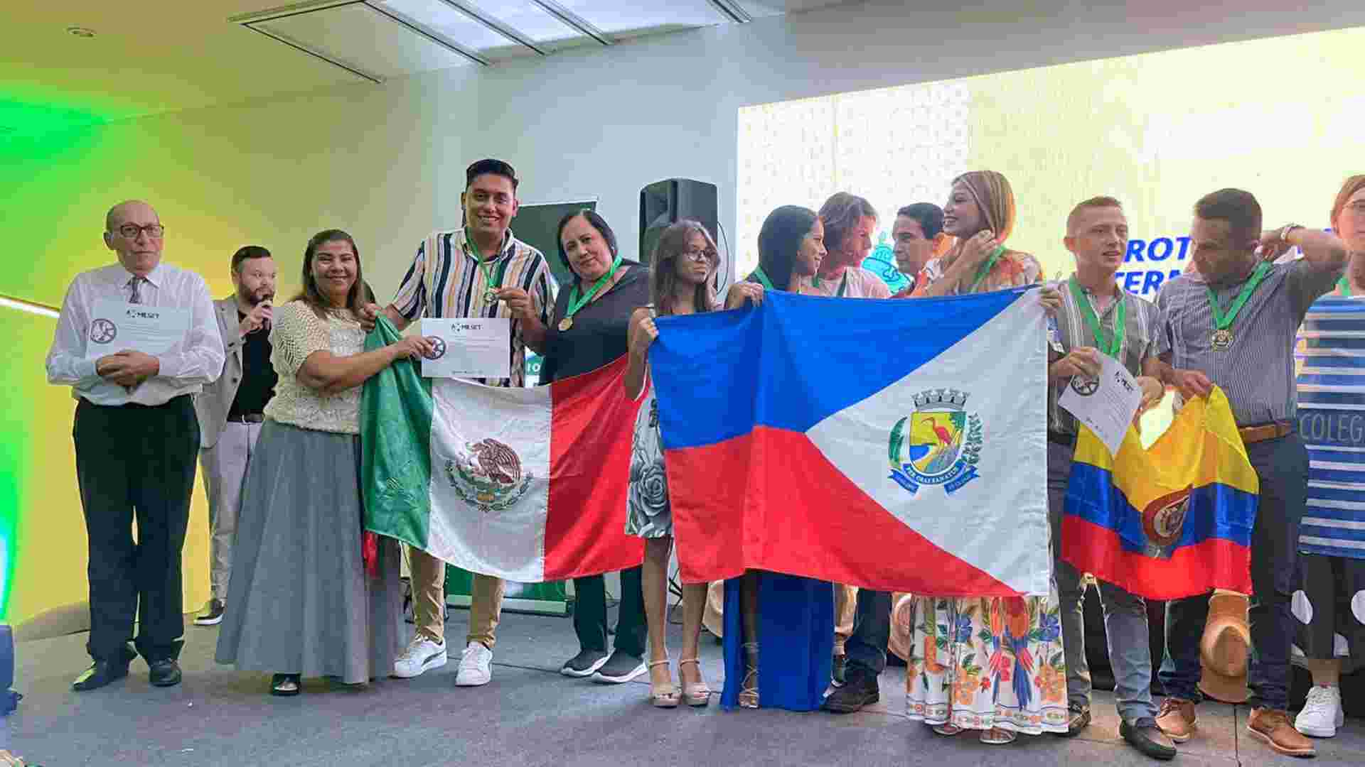 Estudiante y mentoras sostienen bandera de Mexico en competencia internacional de emprendimiento