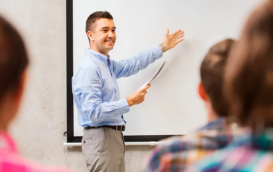 Profesor explicando la clase frente a un pizarrón.