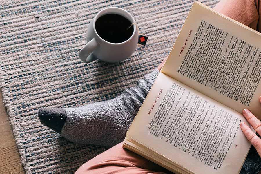 joven leyendo un libro y tomando café