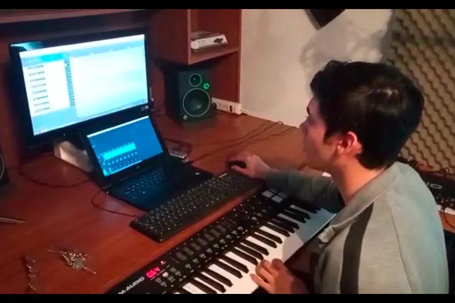 Juan Pablo tocando el teclado con su equipo de sonido en su estudio musical