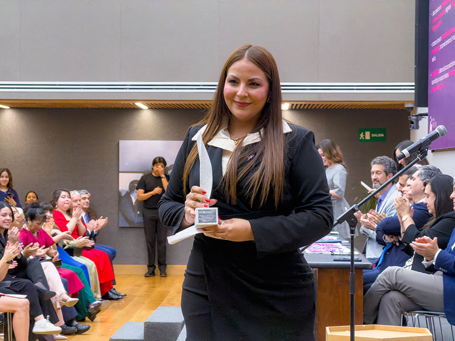 Karina Coronado sosteniendo su reconocimiento