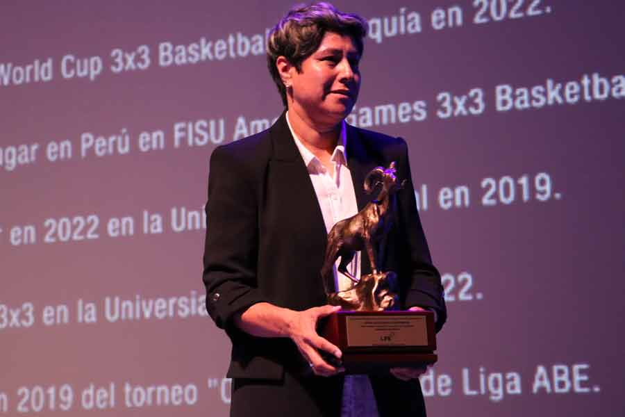 La coach Sandra Rosales con el reconocimiento de la atleta y estudiante Deyna González.