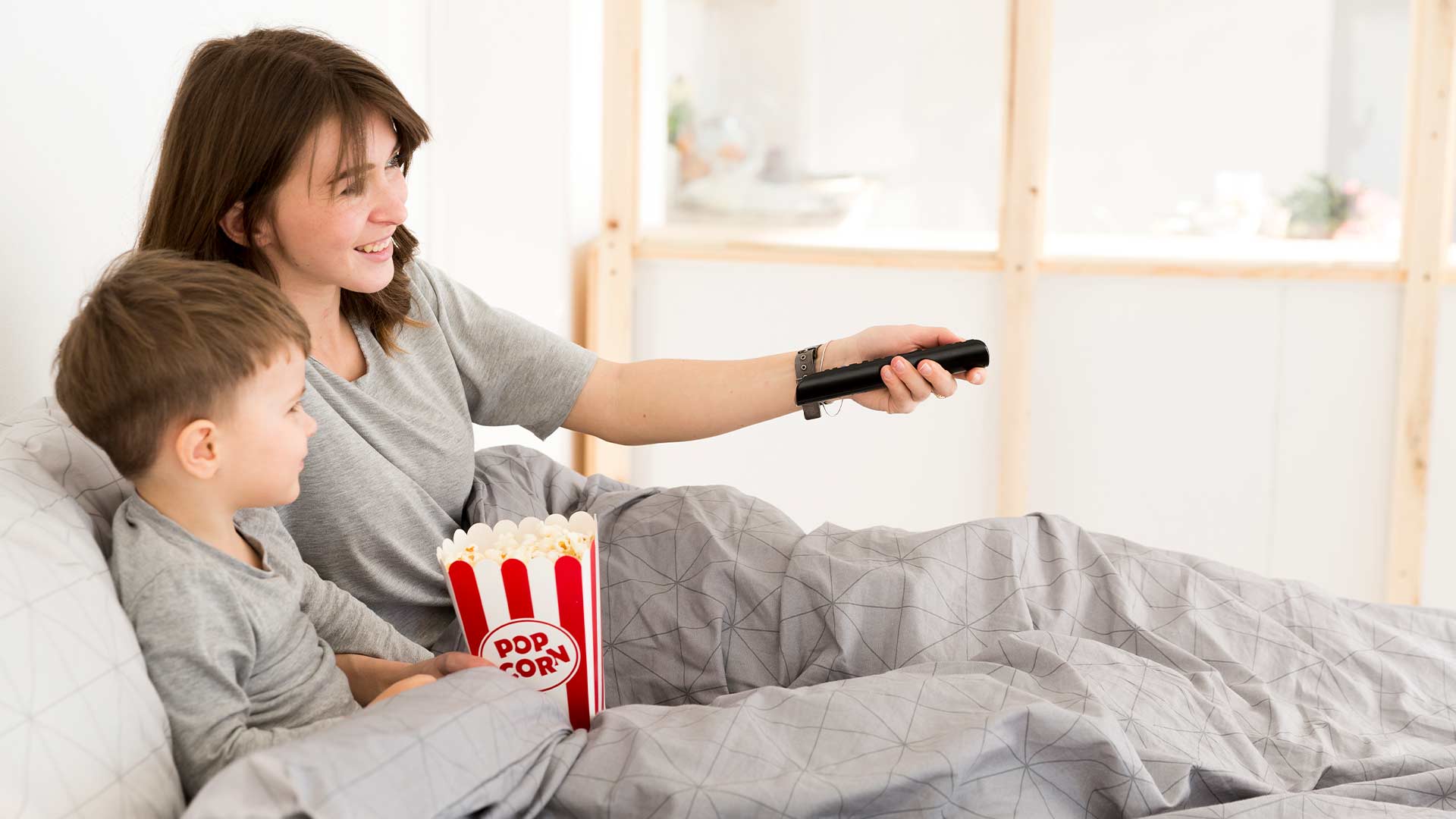 Mamá e hijo viendo una película desde su cama