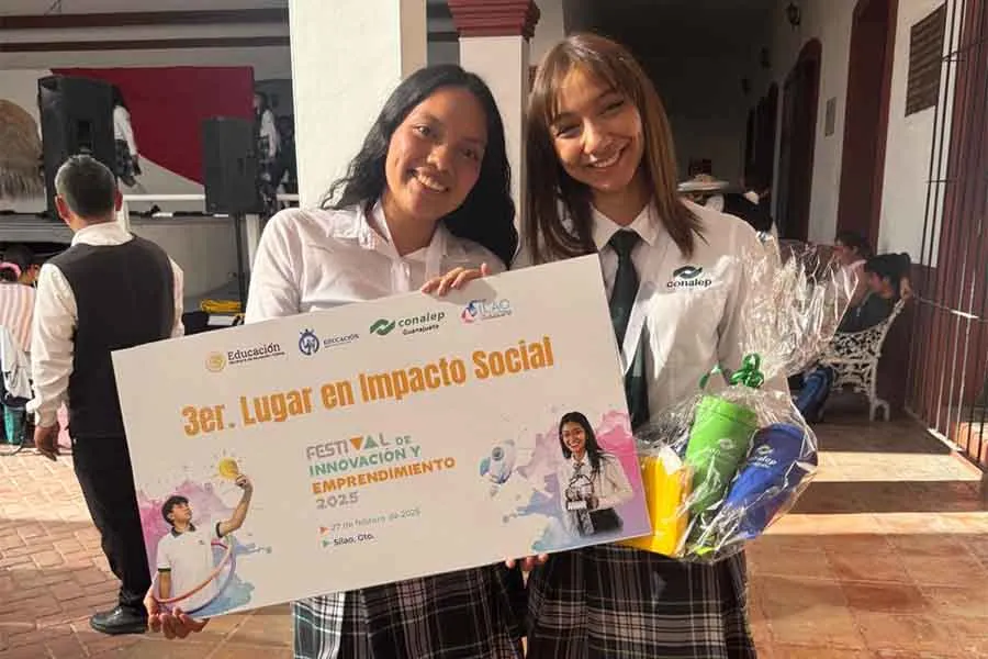 Brenda y su compañera de proyecto recibiendo reconocimiento de Impacto Social