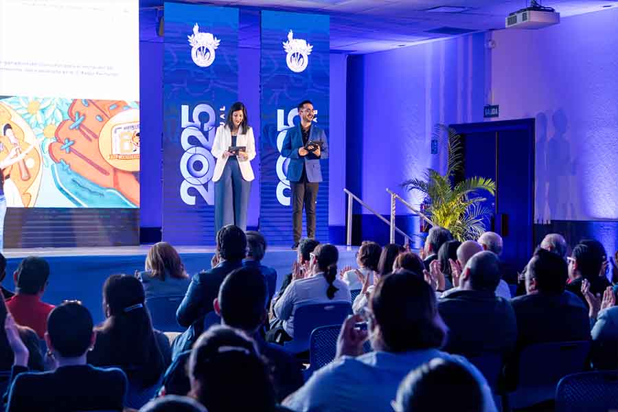 Una mujer y hombre sobre un escenario frente a un público.