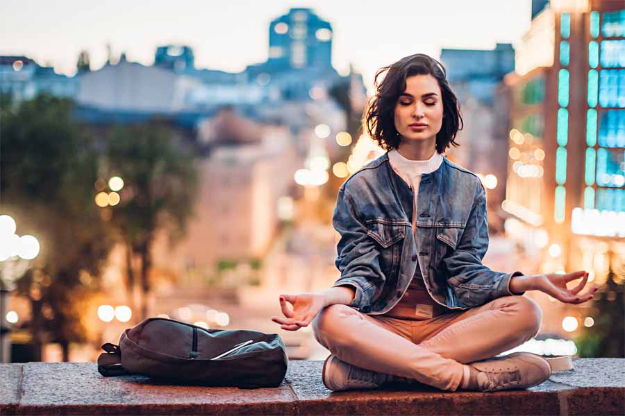 Mujer meditando con luces de ciudad de fondo