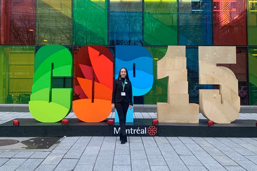 La alumna Sofía Goitia posando junto a letrero de la COP15.