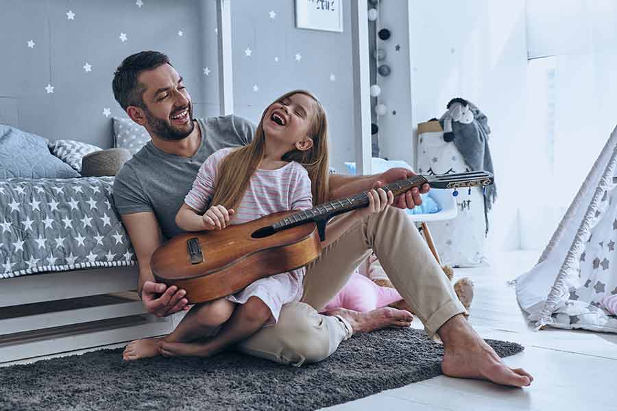 Papá enseñando a su hija a tocar la guitarra