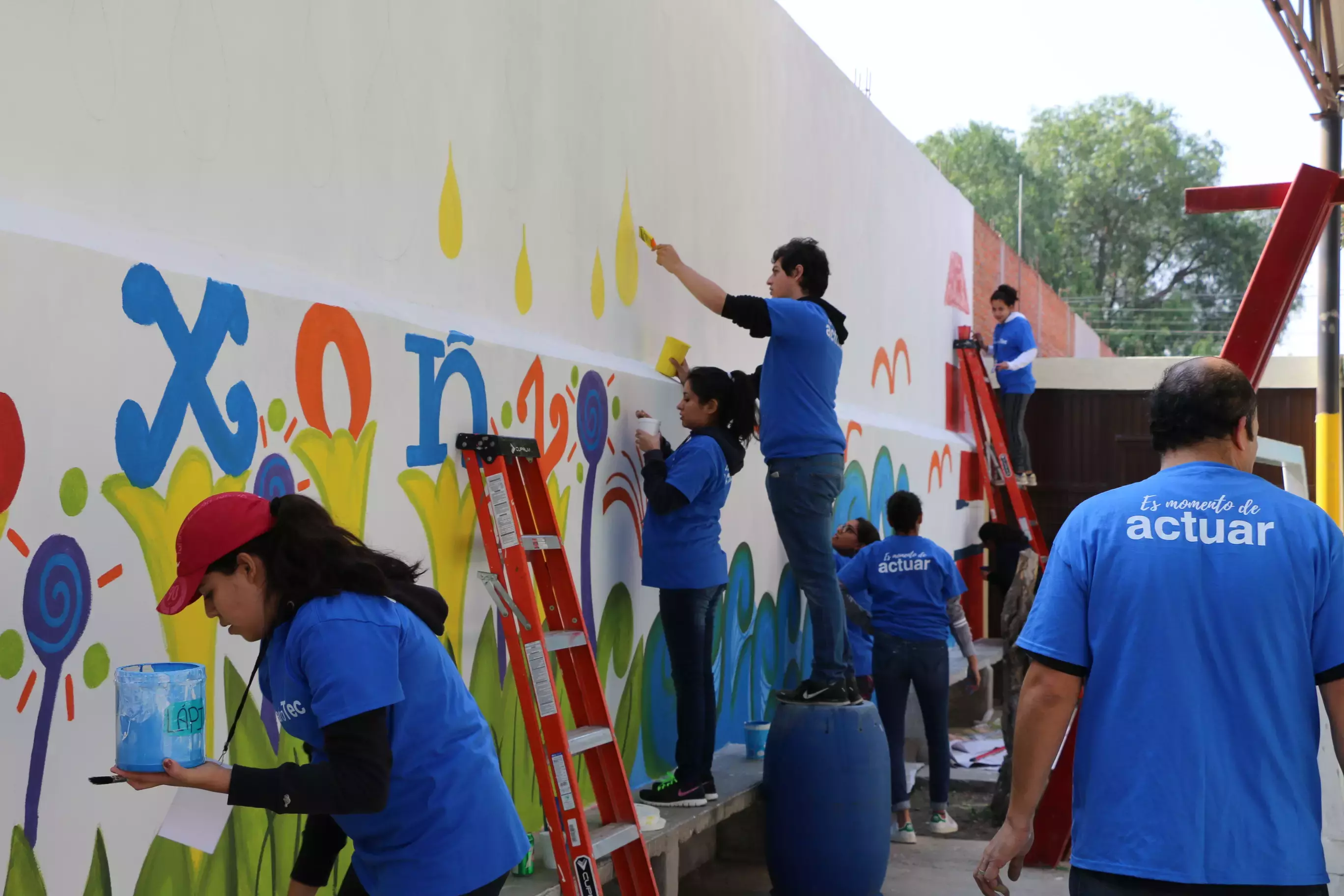 Trabajando en equipo para pintar el mural de la escuela 