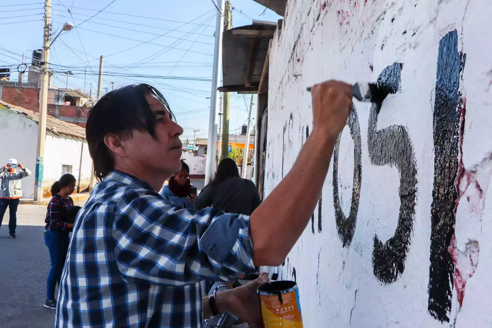 Alumnos y Armando Alanís pintando paredes con frases poéticas