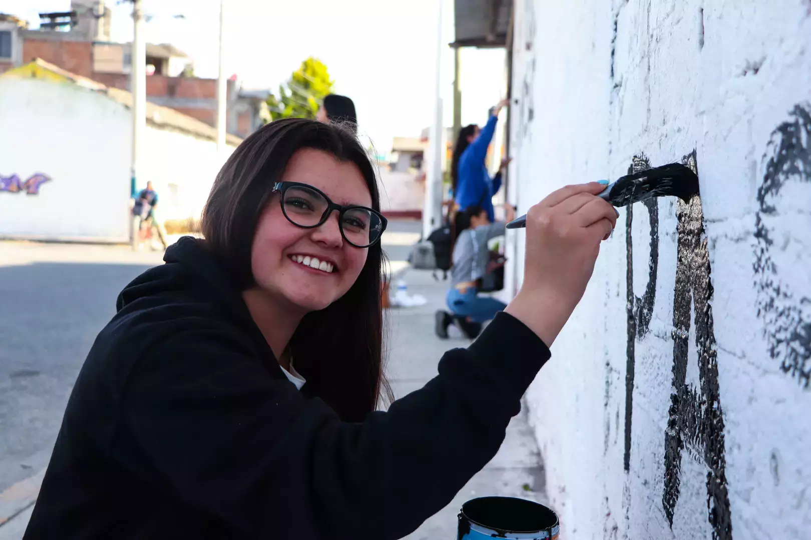 Alumnos y Armando Alanís pintando paredes con frases poéticas