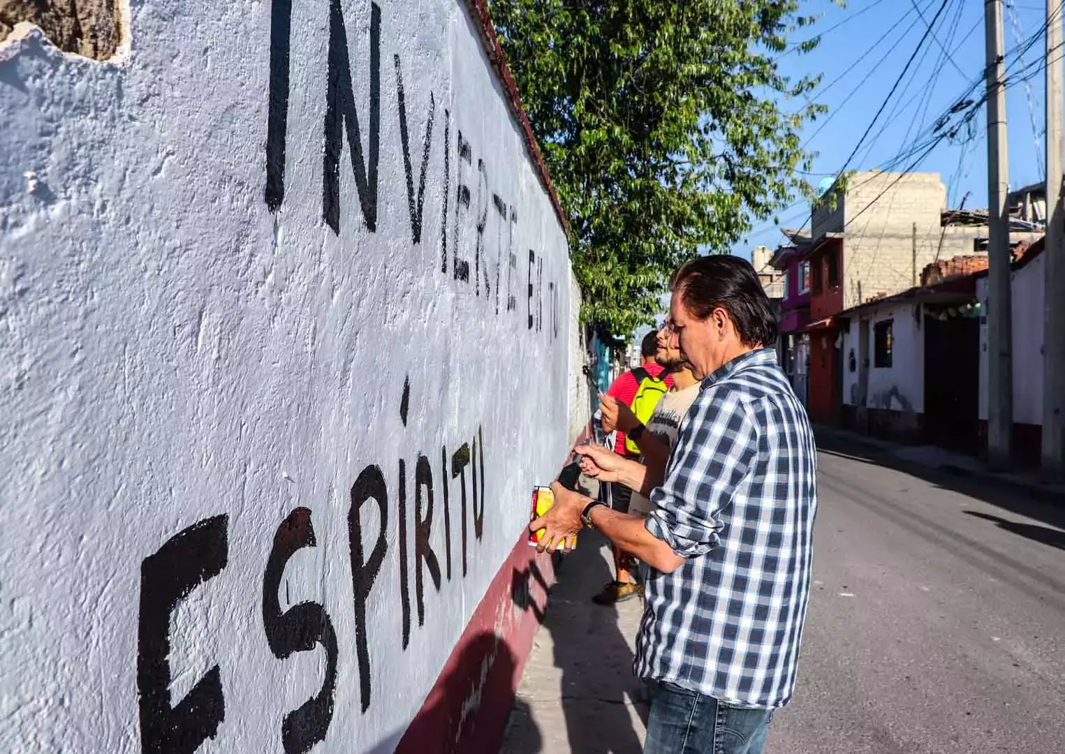 Alumnos y Armando Alanís pintando paredes con frases poéticas