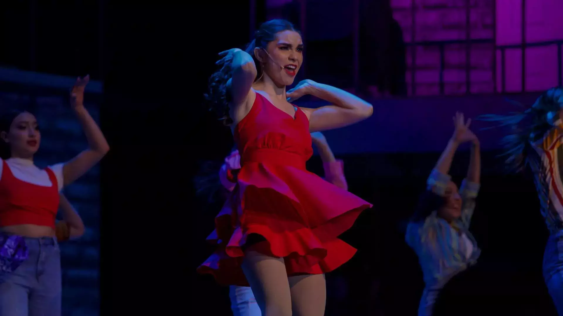 Alumna con vestido rojo baila y canta en escena interpretando a María