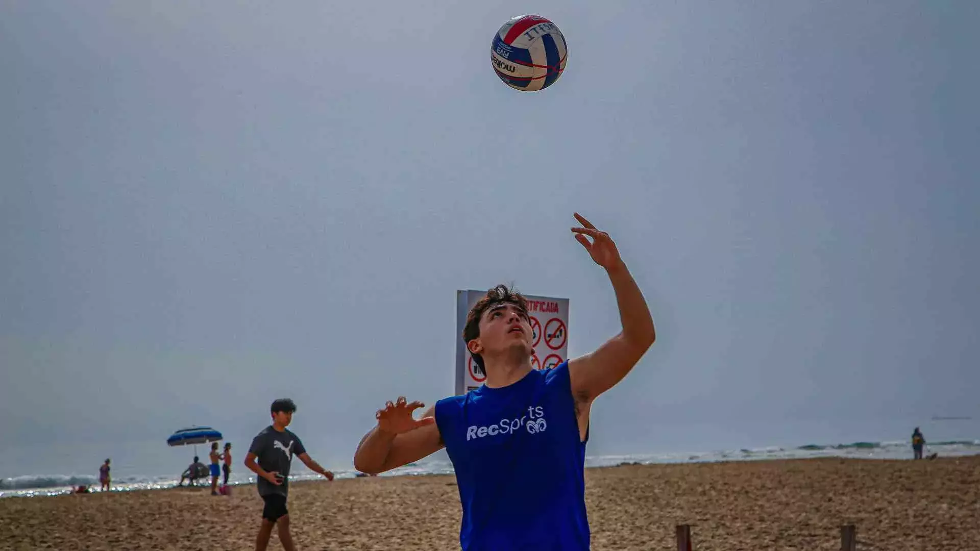 Alumno jugando voleibol en la playa