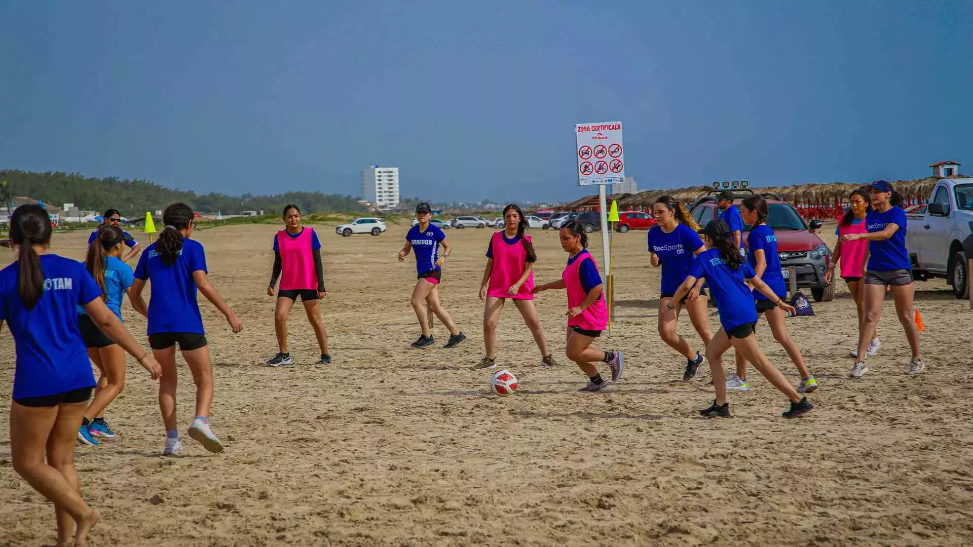 Alumnas jugando fútbol en equipo en la playa