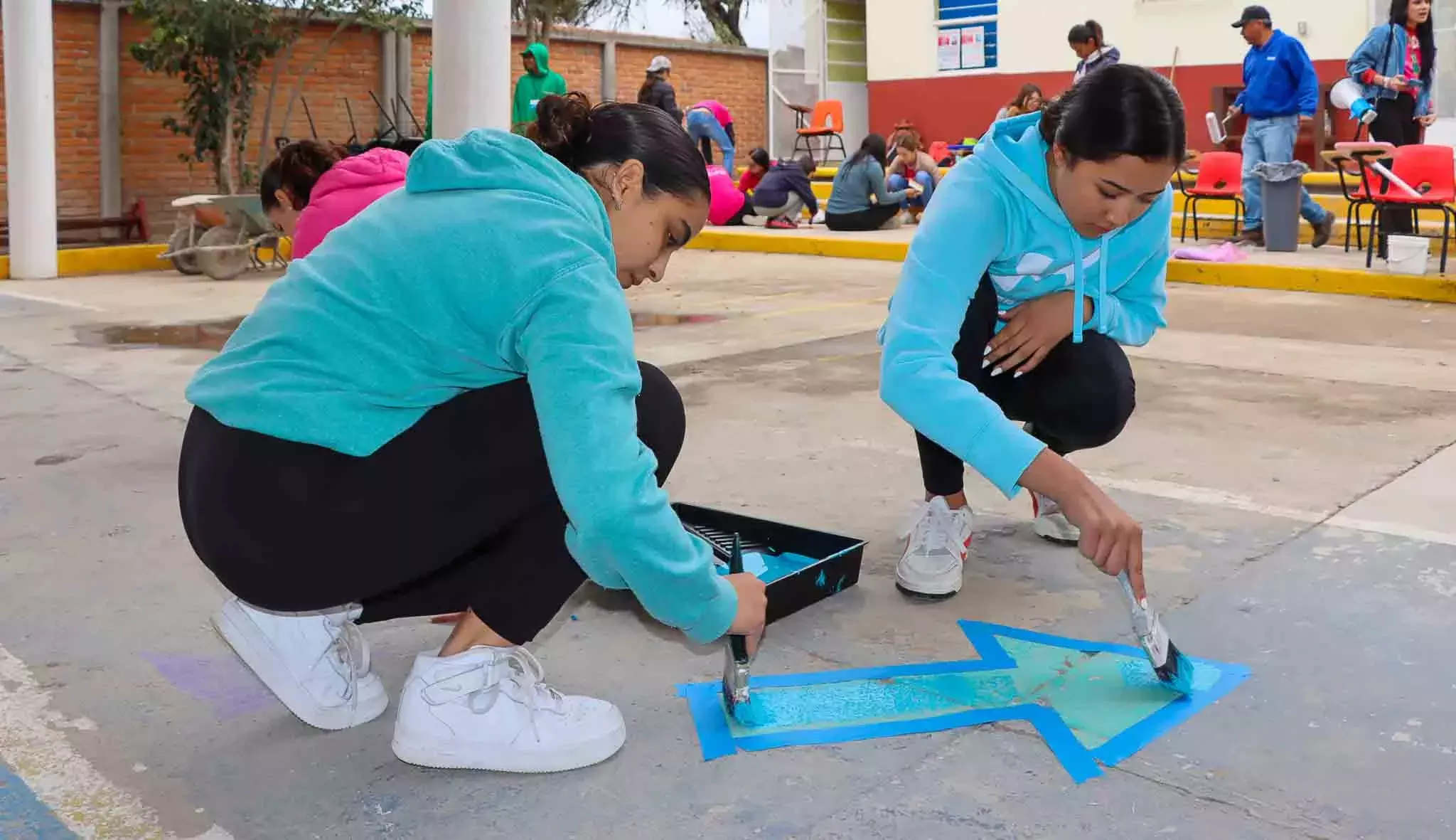 Alumnos pintando el suelo en Voluntariado Tec