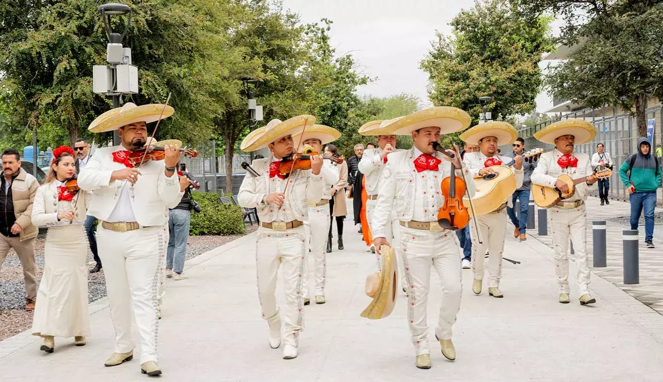 Mariachi va tocando una canción mientras caminan detrás de él los asis