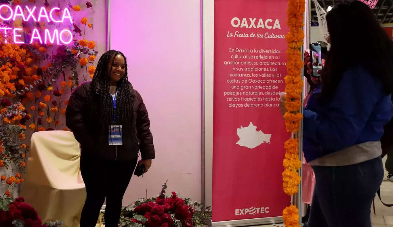 Mujer se fotografía frente a stand de Oaxaca.