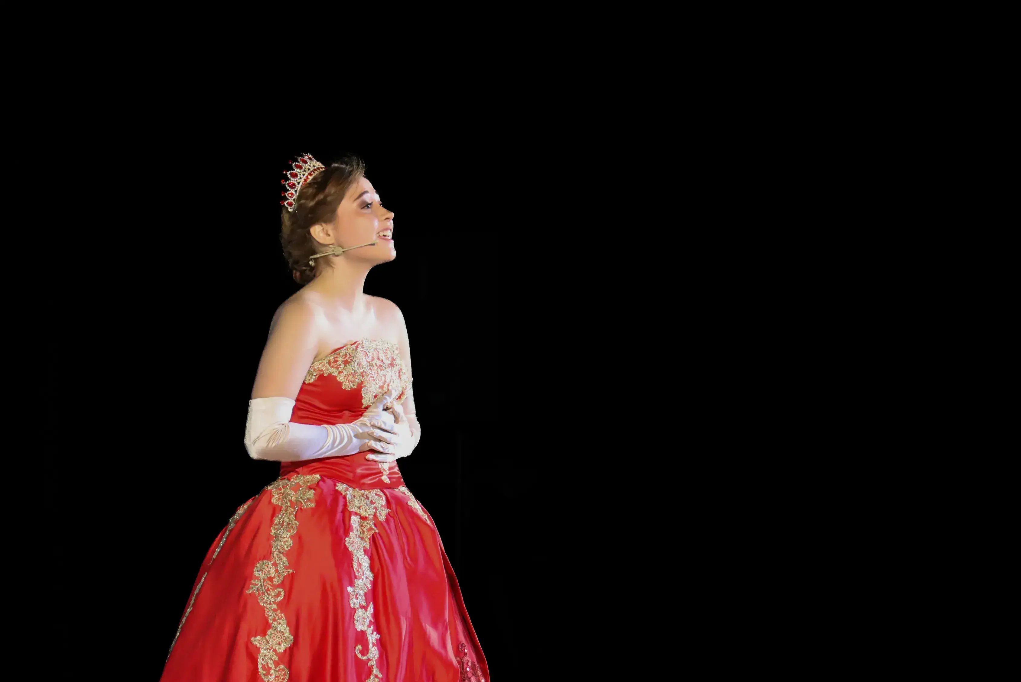 Anastasia cantando, usa un vestido rojo y una corona