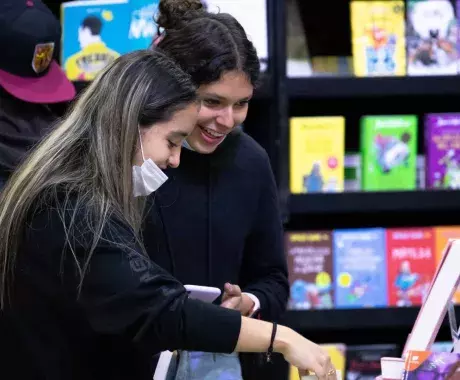 Dos mujeres jóvenes buscan libros en la FIL Monterrey 2022