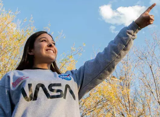 Carolina señalando el cielo con una sudadera de la nasa