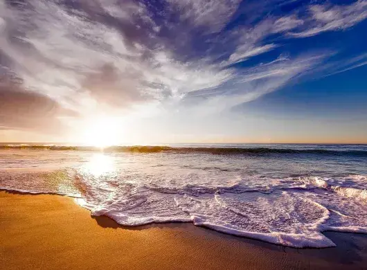 Vista de la playa con el sol de fondo